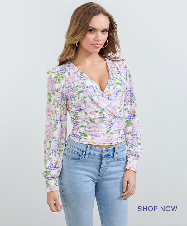 image of a model in a purple floral print wrap long-sleeve top and light-wash jeans | SHOP NOW>